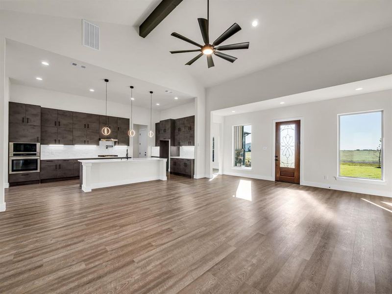 Unfurnished living room with ceiling fan, high vaulted ceiling, beamed ceiling, and hardwood / wood-style floors