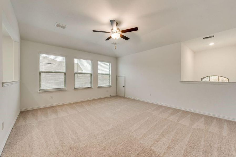 Empty room featuring light colored carpet and ceiling fan