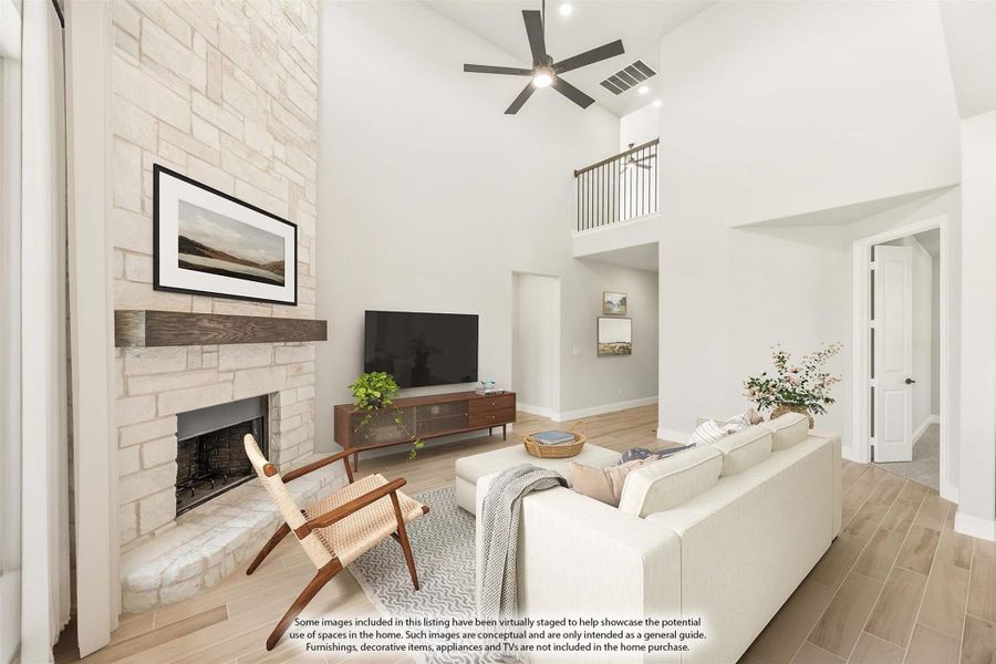 Living room with two-story ceiling, stone fireplace, ceiling fan, and light wood floors Living room with two-story ceiling, stone fireplace, ceiling fan, and light wood floors