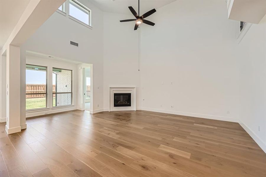 Unfurnished living room with ceiling fan, hardwood / wood-style floors, and high vaulted ceiling