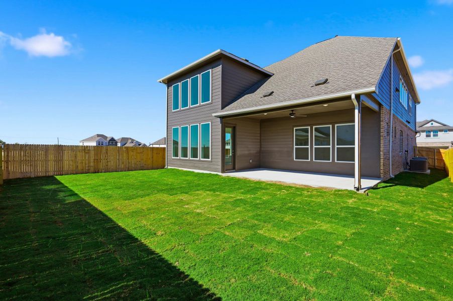 Rear view of property with a fenced backyard, a patio, ceiling fan, roof with shingles, and brick siding