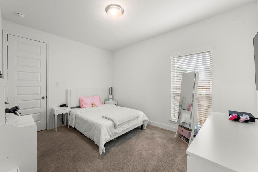 The secondary bedrooms are located in a separate area of the home for privacy. This room features lush carpeting, large walk-in closet, sunny window with 2” blinds, and ceiling light. It has hallway access to the second full bath shared with any house guests.