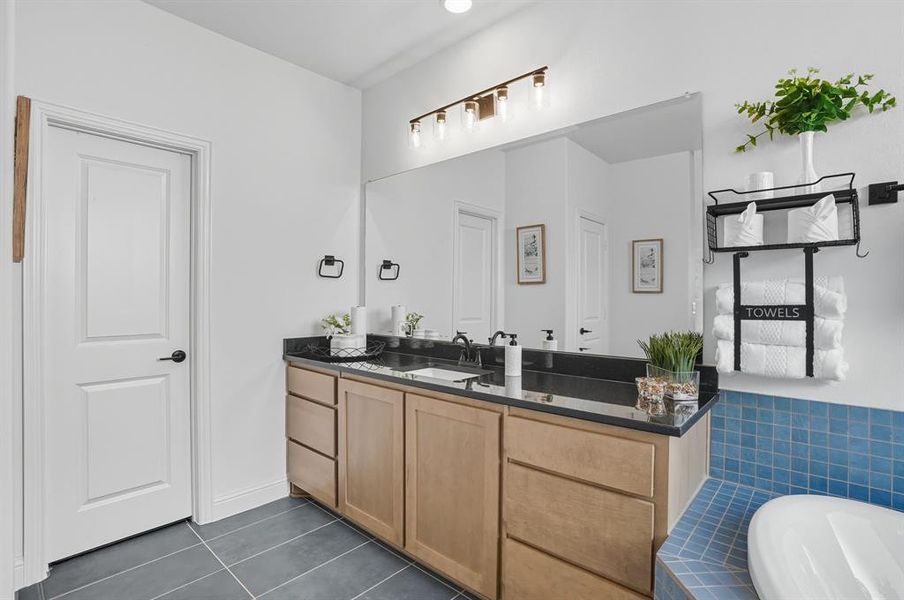Full bath featuring dark tile patterned flooring, vanity, and a garden tub