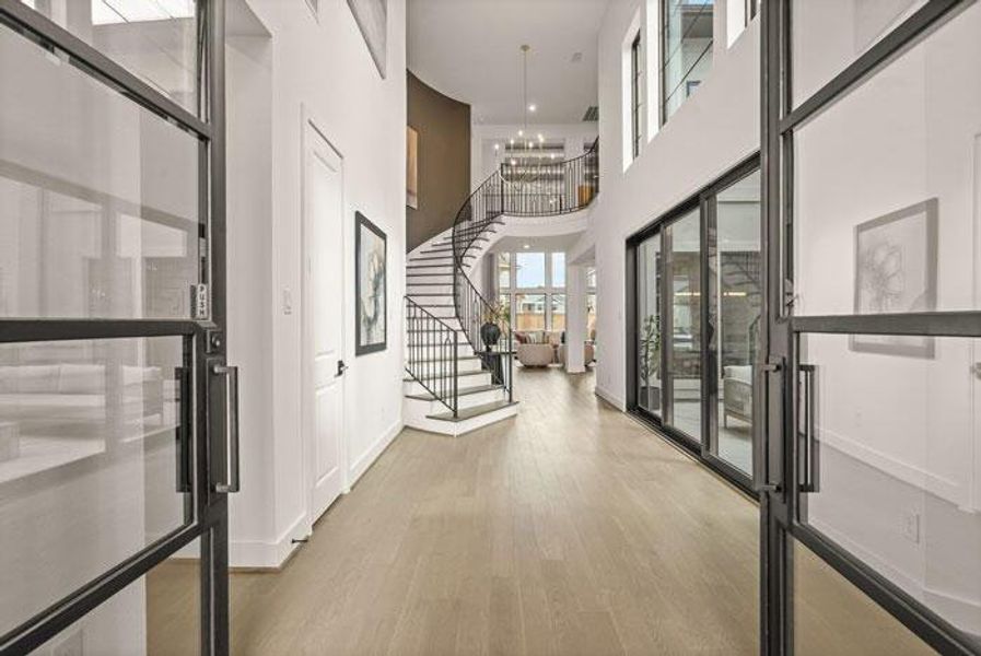 The dazzling grand entry with a curved staircase and courtyard views. Representative image.