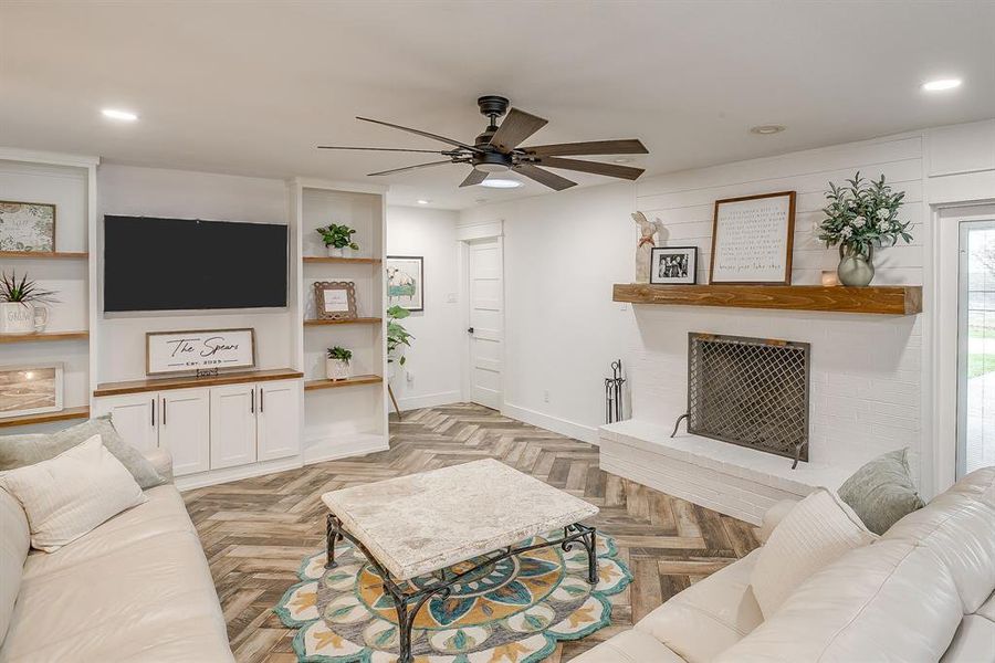 Living area with a ceiling fan, parquet floors, a large fireplace, and recessed lighting