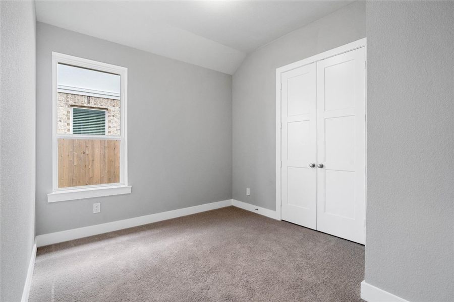 Tucked peacefully in the front of this home is a secondary bedroom perfect for guests or a growing family. It features soft plush carpeting, a large window, sloped ceiling, and ample sized closet space.