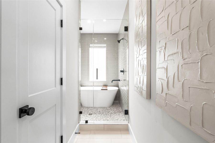 A glass-enclosed wet room separates the bathing area while giving the primary bath a clean, streamlined layout.