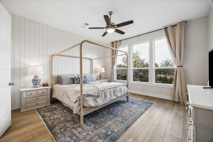The primary suite offers a warm and inviting retreat, highlighted by a beautiful shiplap accent wall and large windows that fill the room with natural light.