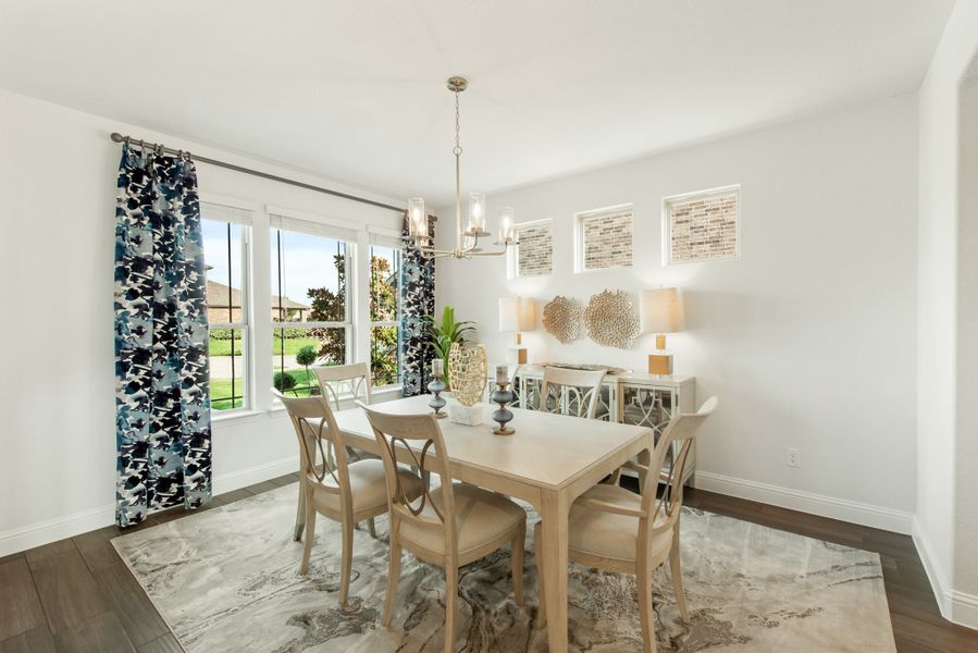 Dining room with wood table, four chairs, chandelier, and large windows with patterned curtains
