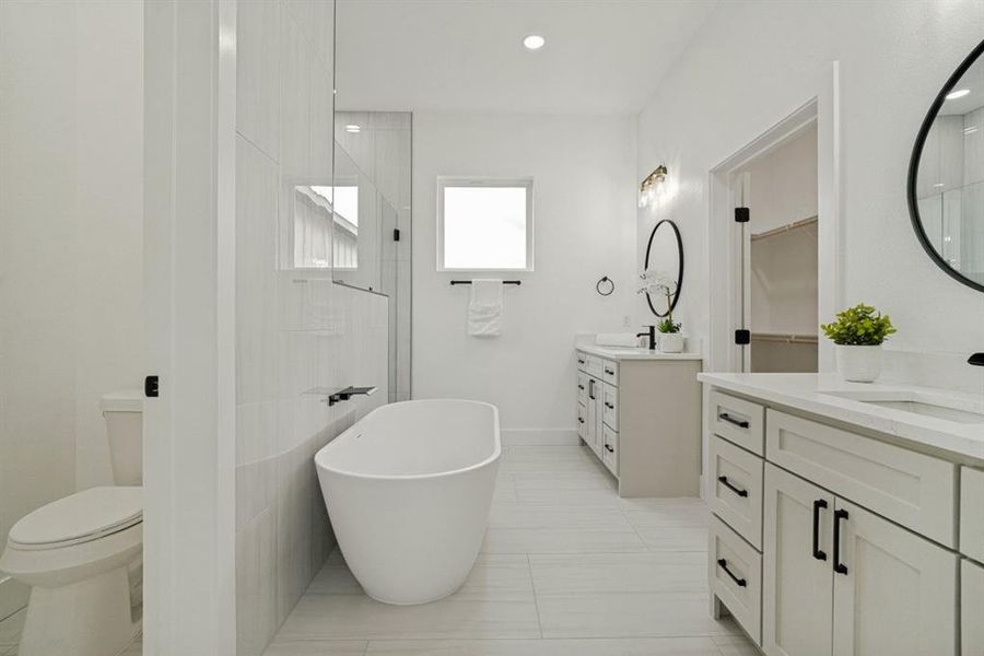 Contemporary bathroom featuring a freestanding soaking tub, dual vanities with white countertops, and a walk-in shower with clear glass enclosure Contemporary bathroom featuring a freestanding soaking tub, dual vanities with white countertops, and a walk-in shower with clear glass enclosure