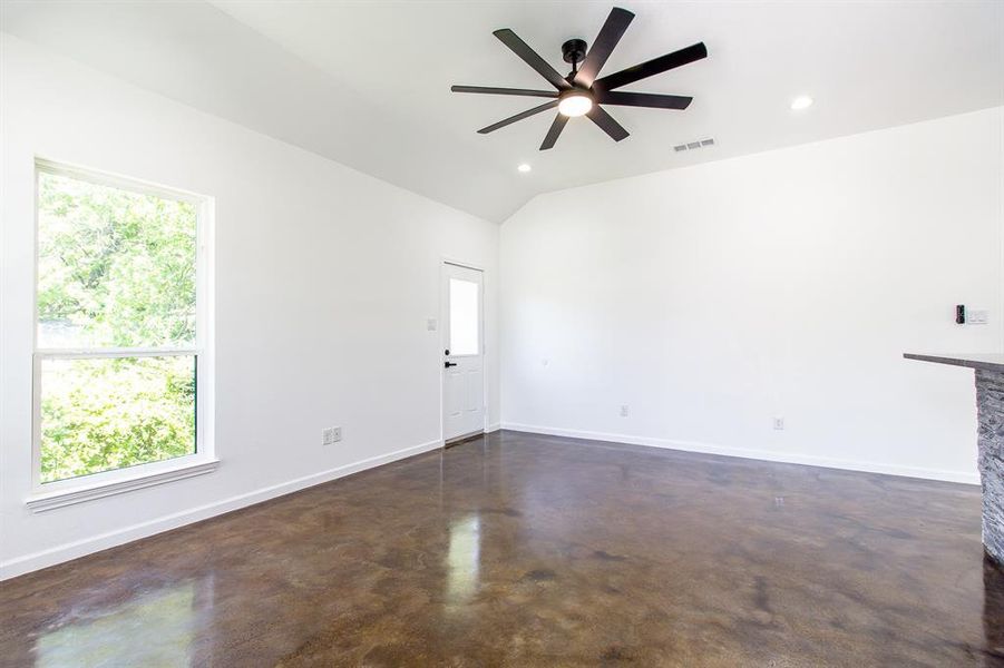 Unfurnished living room featuring a wealth of natural light, ceiling fan, and lofted ceiling