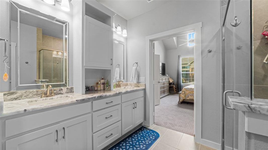 Bathroom featuring tile floors, dual vanity, walk in shower, and vaulted ceiling