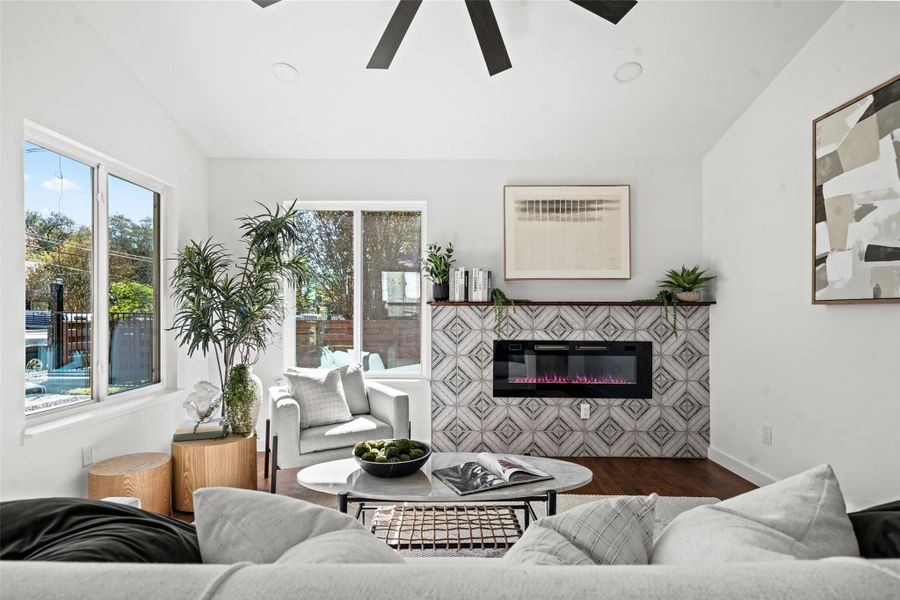 Living room featuring wood finished floors, lofted ceiling, a glass covered fireplace, recessed lighting, and ceiling fan