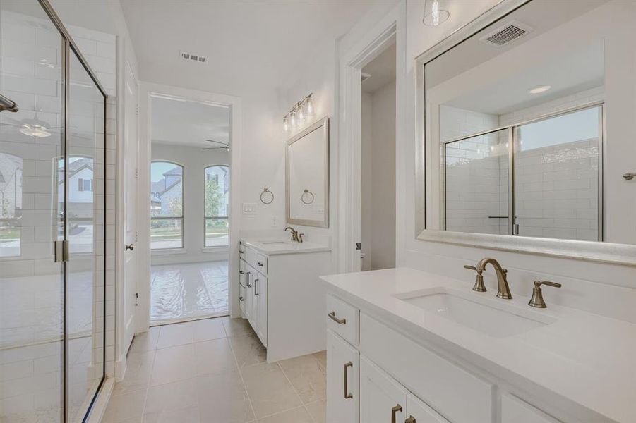Bathroom featuring twin vanities with integrated sinks, brushed bronze fixtures, and framed mirrors