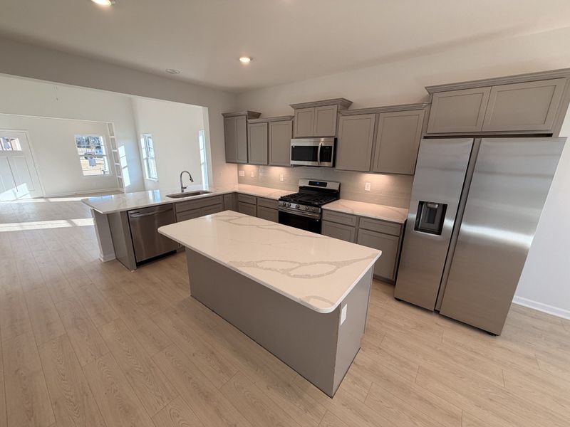 Gorgeous kitchen fully equipped with stainless steel appliances, ceramic tile backsplash and quartz kitchen countertops perfect for gathering around the kitchen on this open floorplan