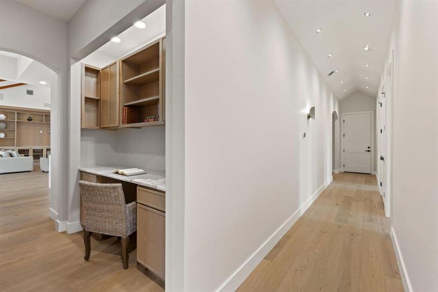 Hall with arched walkways, recessed lighting, light
wood-style floors, a desk, and lofted ceiling Hall with arched walkways, recessed lighting, light
wood-style floors, a desk, and lofted ceiling