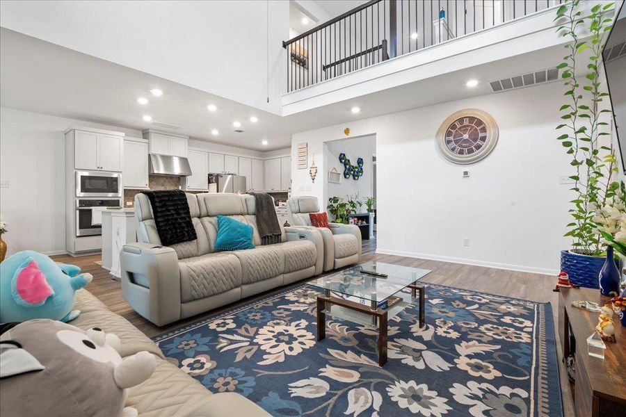 Living room featuring recessed lighting, light wood-style flooring, and a high ceiling