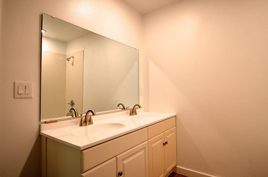 Full bathroom with double vanity and a textured wall