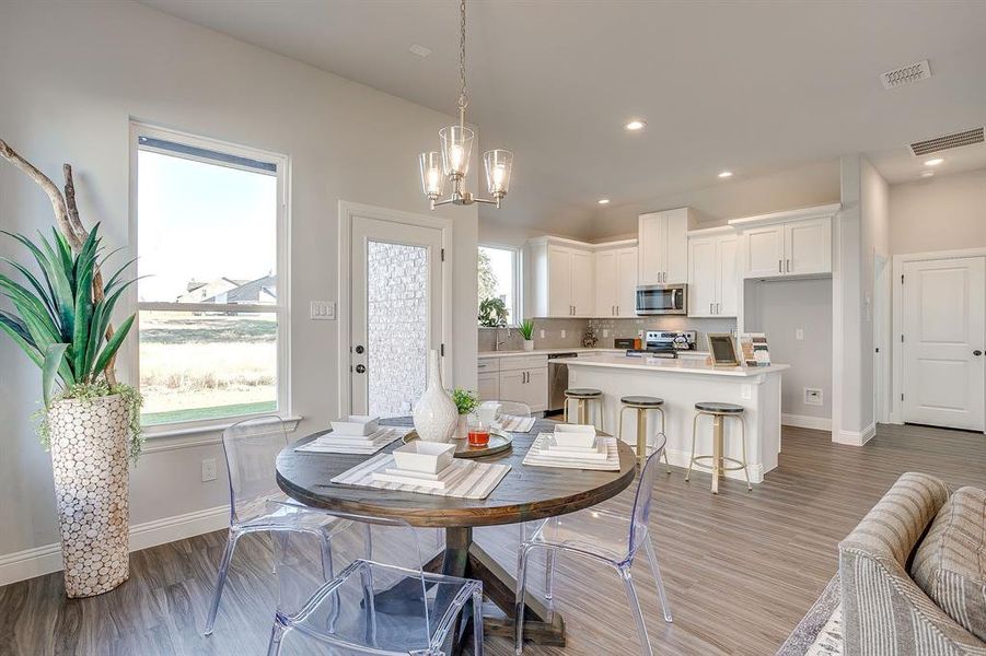 Dining room with light wood finished floors, a chandelier, and recessed lighting