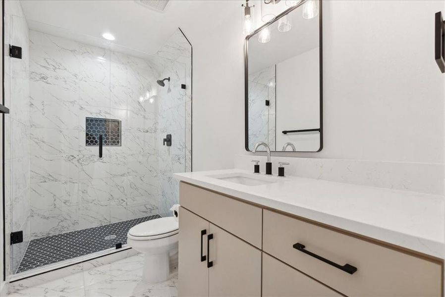 Bathroom featuring vanity, toilet, and a shower with door