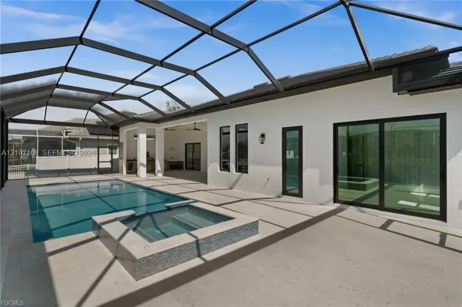 Screened-in lanai featuring a swimming pool, integrated spa with tile detailing, paved flooring, and glass sliding doors