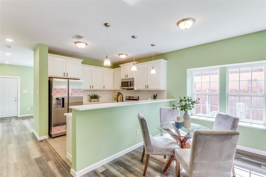 Kitchen with appliances with stainless steel finishes, white cabinets, and light wood-type flooring