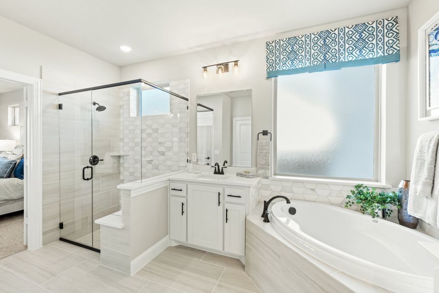 Master bathroom with glass walk-in shower, soaking tub, and white vanity with tile floors Master bathroom with glass walk-in shower, soaking tub, and white vanity with tile floors