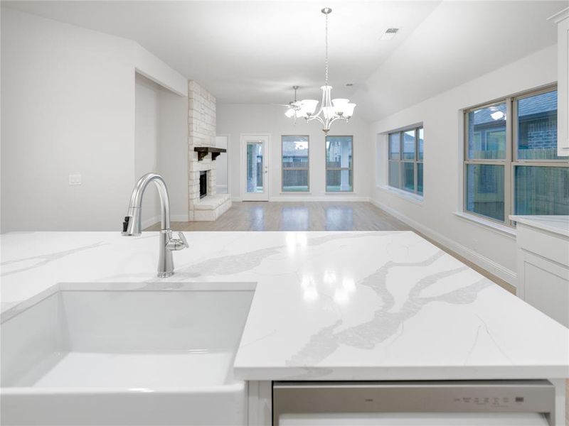 Kitchen featuring decorative light fixtures, a fireplace, light stone countertops, and sink