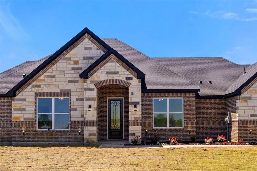 View of front of house with brick siding, stone siding, and a front yard View of front of house with brick siding, stone siding, and a front yard
