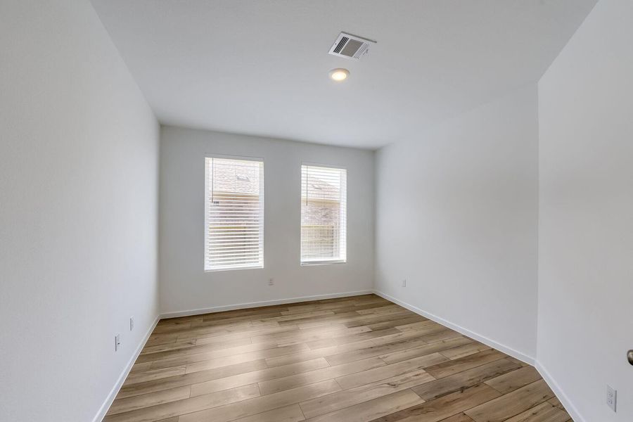 Bright and versatile space perfect for a home office, featuring ample natural light and sleek flooring.