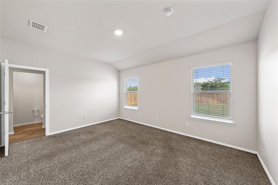 Unfurnished room featuring dark colored carpet, lofted ceiling, and a smoke detector Unfurnished room featuring dark colored carpet, lofted ceiling, and a smoke detector
