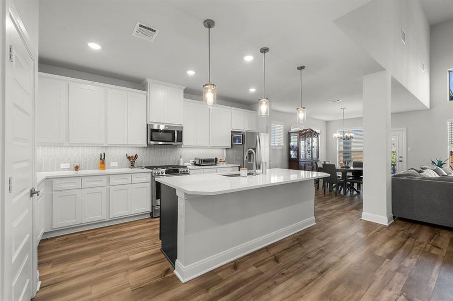Kitchen with open floor plan, tasteful backsplash, a kitchen island with sink, white cabinets, and recessed lighting Kitchen with open floor plan, tasteful backsplash, a kitchen island with sink, white cabinets, and recessed lighting