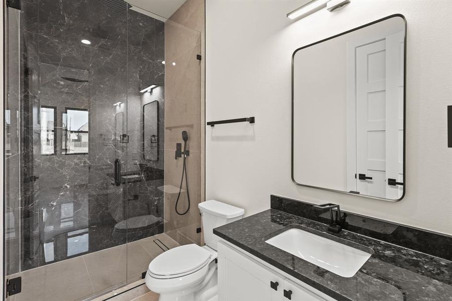 Bathroom featuring vanity, toilet, and a shower with door