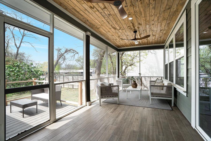 Spacious screened porch featuring a wooden plank ceiling with ceiling fans, wood-look flooring, and access to an outdoor deck and yard Spacious screened porch featuring a wooden plank ceiling with ceiling fans, wood-look flooring, and access to an outdoor deck and yard