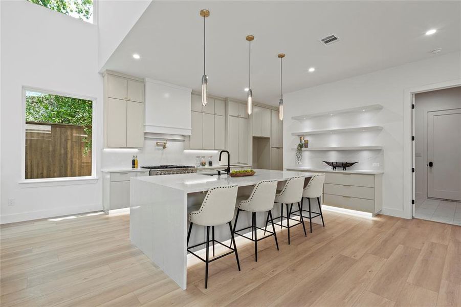 Kitchen with light wood finished floors, modern cabinets, a kitchen island with sink, premium range hood, and recessed lighting