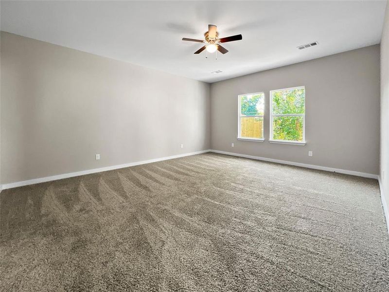 Carpeted empty room with ceiling fan and baseboards