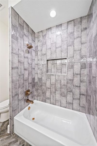 Bathtub and shower combination featuring gray subway tile surround and bronze-finish fixtures