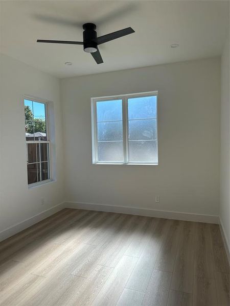 Empty room with ceiling fan and light hardwood / wood-style flooring