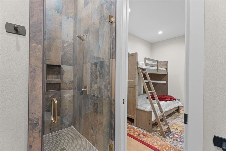 Full bathroom with a stall shower, wood finished floors, ornamental molding, and a textured wall