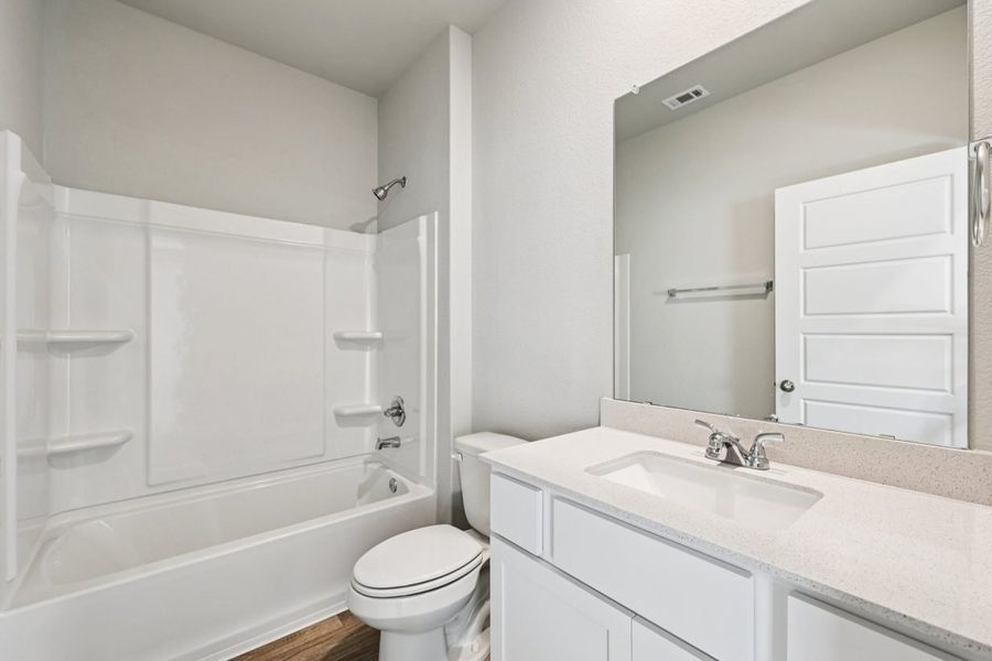 Image of a bathroom with a white dual vanity, large mirror, a shower and tub, and white cabinets