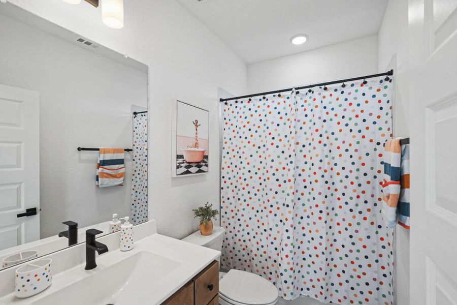Fresh and functional full bath featuring a sleek vanity, modern fixtures, and a bright, cheerful design. Clean lines and ample lighting create a welcoming space for family and guests.
