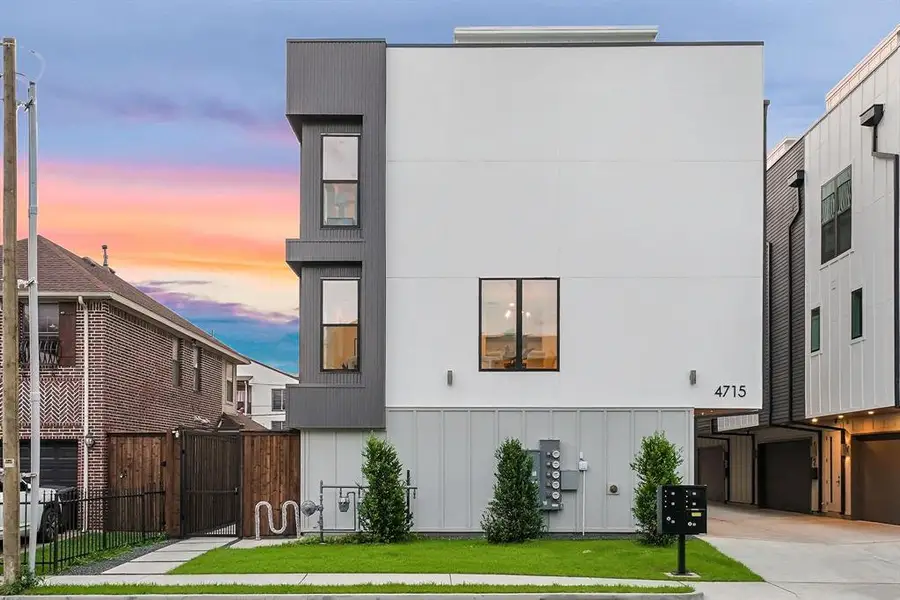 Modern multi-level residence featuring a white and gray facade, multiple windows, a manicured lawn, and a paved walkway Modern multi-level residence featuring a white and gray facade, multiple windows, a manicured lawn, and a paved walkway