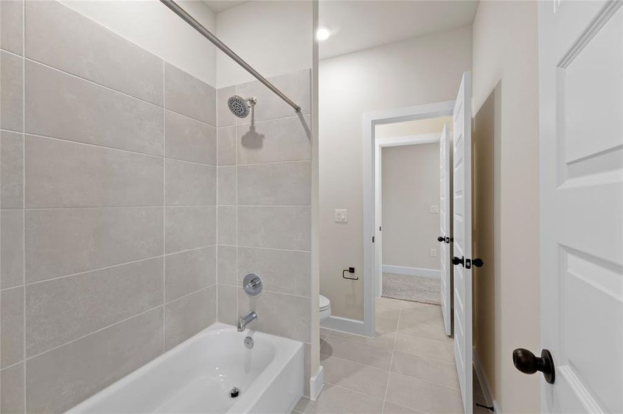 Bathroom with washtub / shower combination and light tile patterned floors Bathroom with washtub / shower combination and light tile patterned floors