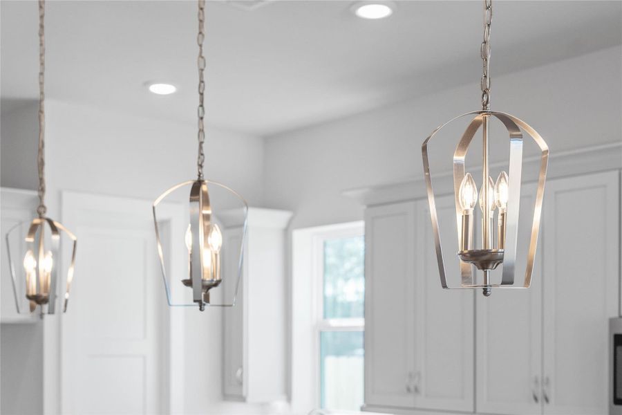 Contemporary pendant lights hang above the island, adding a touch of modern design, complemented by recessed lighting throughout the ceiling for overall illumination.