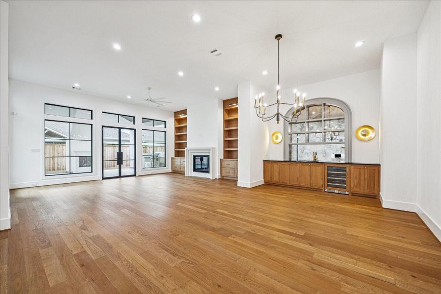 Warm oak cabinetry stretches across the back wall, creating a refined serving and storage zone beneath soft gold sconces. An arched mirror introduces architectural depth and anchors the space with timeless character. Warm oak cabinetry stretches across the back wall, creating a refined serving and storage zone beneath soft gold sconces. An arched mirror introduces architectural depth and anchors the space with timeless character.