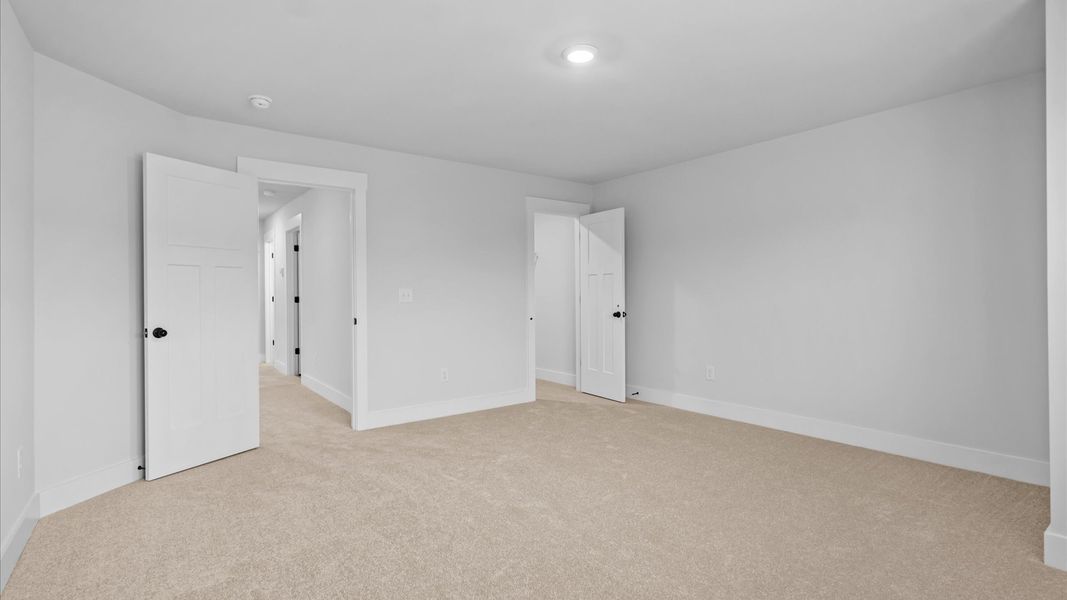 Tasteful secondary bedroom with plush carpet and a spacious walk-in closet at Silo Ridge by DRB Homes in Anderson, SC