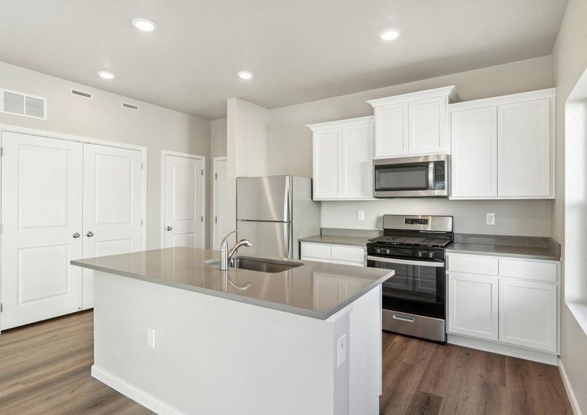 The kitchen has stainless steel appliances and plank flooring.