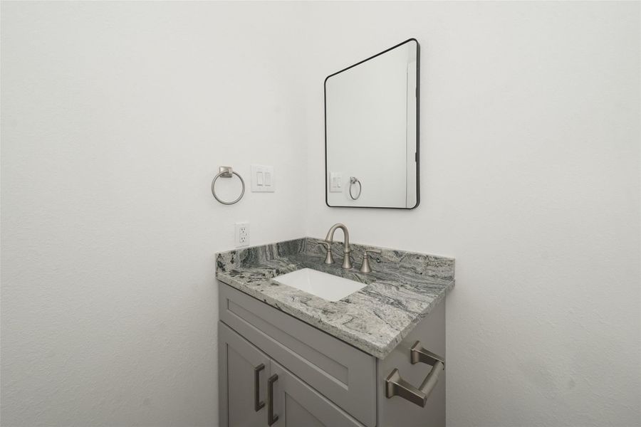 Modern kitchen with sleek white cabinetry, stainless steel appliances, and a striking granite double waterfall island. Features a spacious open layout with wood flooring, pendant lighting, and ample natural light from large windows.