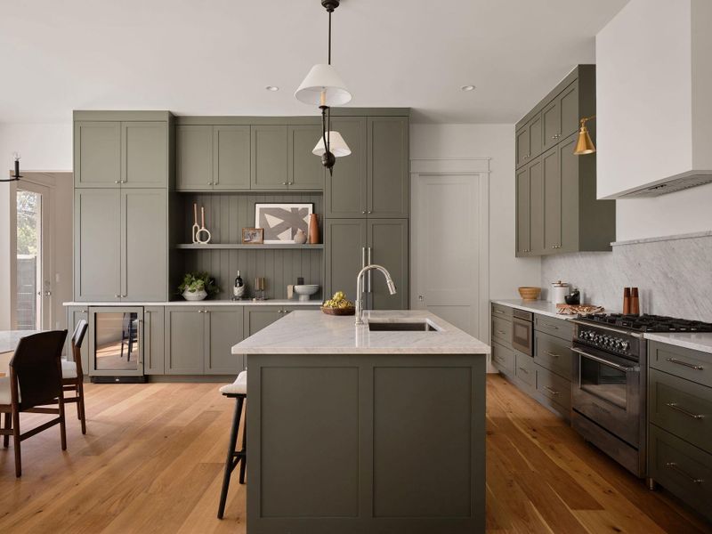 Kitchen featuring pendant lighting, open shelves, stainless steel appliances, an island with sink, and beverage cooler Kitchen featuring pendant lighting, open shelves, stainless steel appliances, an island with sink, and beverage cooler