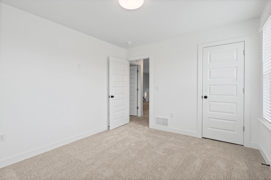 Wall-to-wall carpeting, window with blinds, white panel doors, and overhead lighting